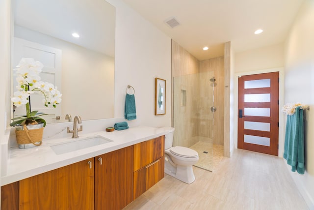 bathroom with vanity, tiled shower, and toilet