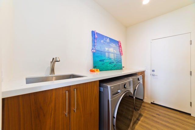 laundry area with sink, washer and clothes dryer, cabinets, and wood-type flooring