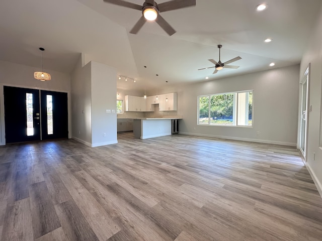 unfurnished living room featuring ceiling fan, light hardwood / wood-style flooring, and lofted ceiling