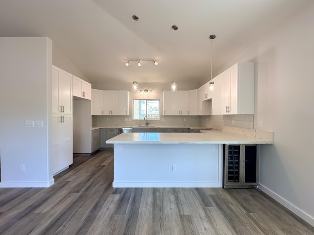 kitchen featuring decorative backsplash, white cabinetry, kitchen peninsula, and sink