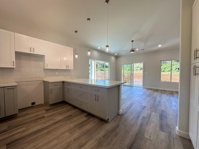 kitchen featuring lofted ceiling, kitchen peninsula, decorative backsplash, ceiling fan, and wood-type flooring