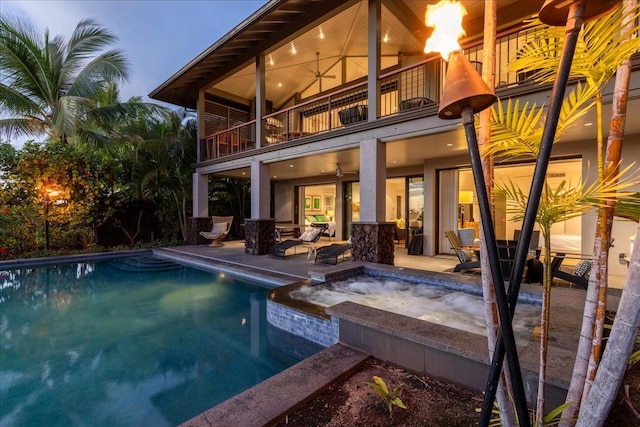 back of house with a patio, ceiling fan, a balcony, and a swimming pool with hot tub