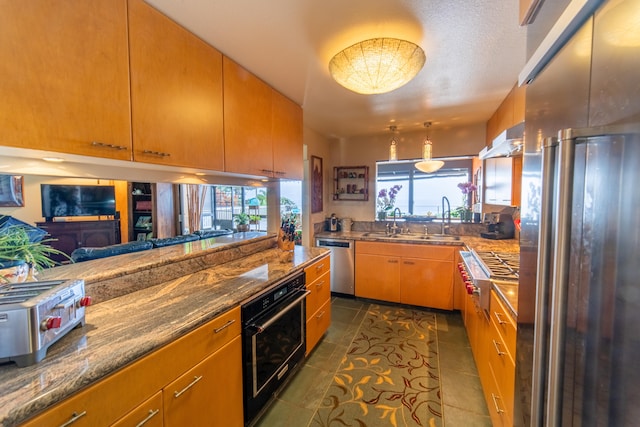 kitchen featuring sink, stainless steel appliances, dark tile patterned floors, dark stone countertops, and extractor fan