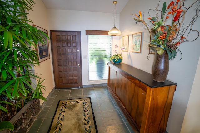 entrance foyer featuring dark tile patterned floors and lofted ceiling