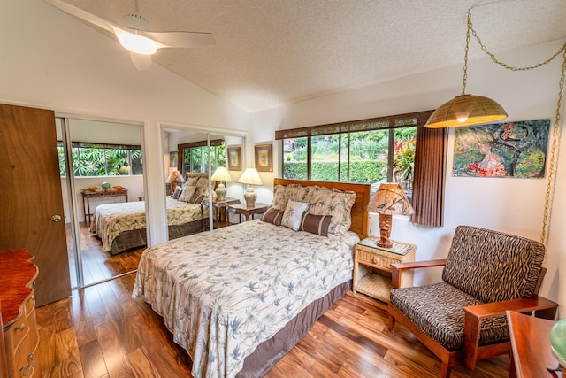 bedroom with a textured ceiling, hardwood / wood-style flooring, ceiling fan, and lofted ceiling