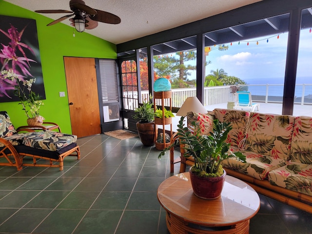 tiled living room featuring a textured ceiling, ceiling fan, a water view, and vaulted ceiling