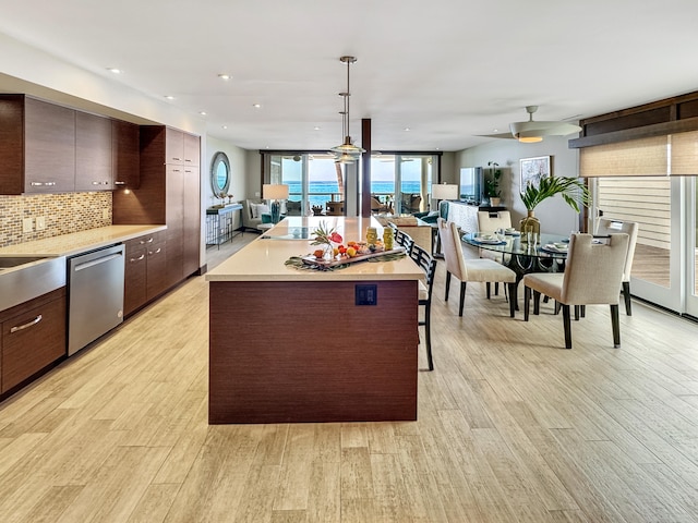 kitchen with tasteful backsplash, stainless steel dishwasher, dark brown cabinetry, decorative light fixtures, and light hardwood / wood-style floors