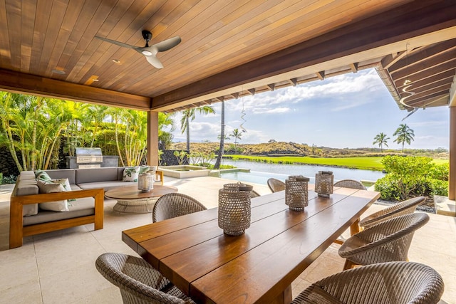 view of patio / terrace with ceiling fan, a water view, a hot tub, exterior kitchen, and a grill