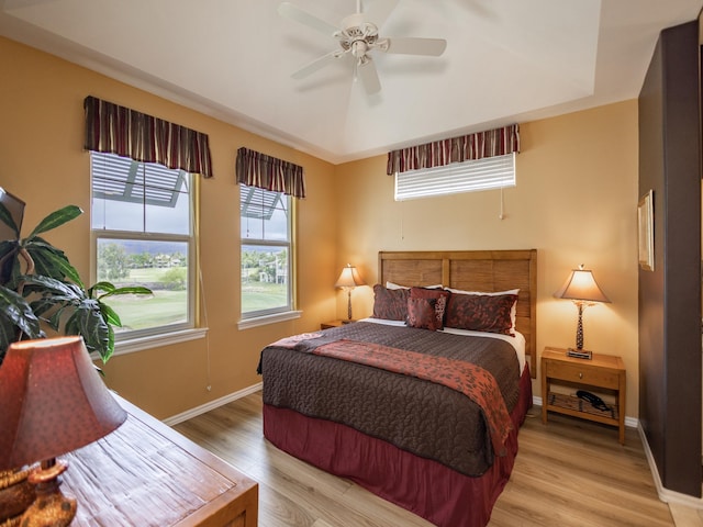 bedroom featuring a tray ceiling, light hardwood / wood-style flooring, and ceiling fan