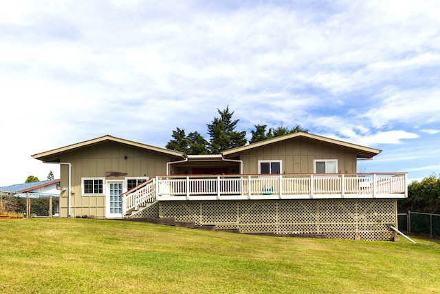 rear view of property featuring a wooden deck and a lawn