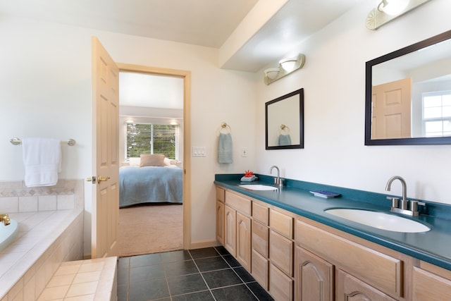 bathroom featuring tile patterned flooring, vanity, a healthy amount of sunlight, and tiled tub