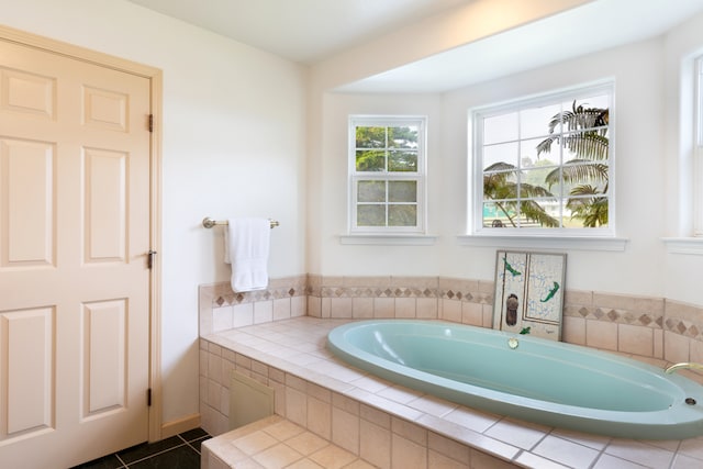 bathroom with a relaxing tiled tub and tile patterned floors