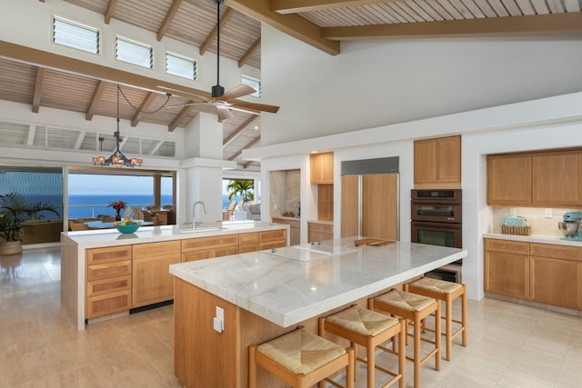 kitchen featuring a kitchen breakfast bar, black electric cooktop, a center island, and paneled refrigerator