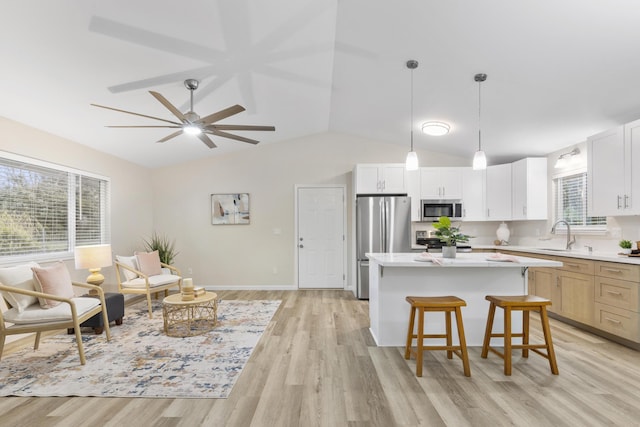 kitchen featuring stainless steel appliances, white cabinetry, decorative light fixtures, and a center island