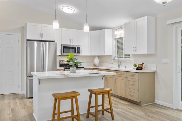 kitchen with white cabinets, appliances with stainless steel finishes, sink, and a center island