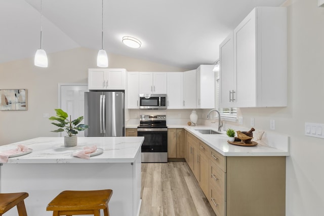 kitchen featuring stainless steel appliances, decorative light fixtures, vaulted ceiling, white cabinets, and sink