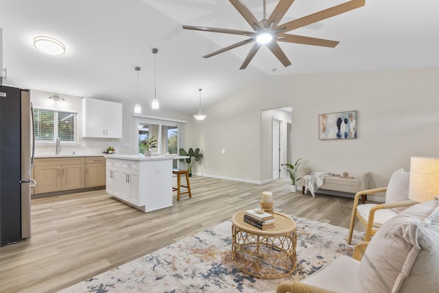 living room with ceiling fan, sink, light hardwood / wood-style floors, and lofted ceiling