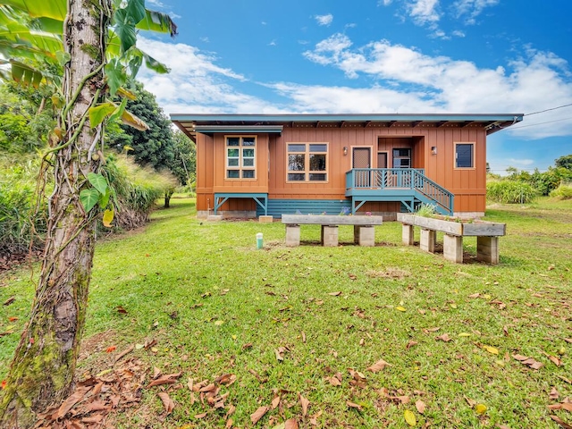 rear view of property with board and batten siding and a yard