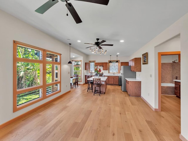 kitchen featuring brown cabinets, light wood finished floors, a breakfast bar area, light countertops, and a kitchen island