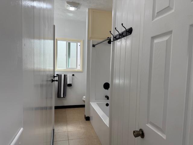 bathroom with toilet, tile patterned flooring, and bathtub / shower combination