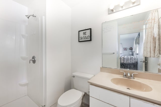 bathroom featuring toilet, vanity, and walk in shower