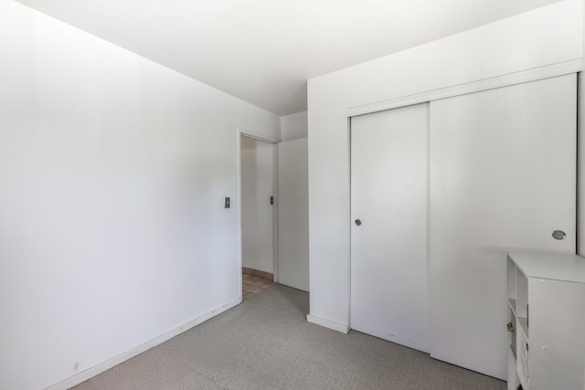 unfurnished bedroom with light carpet and a closet