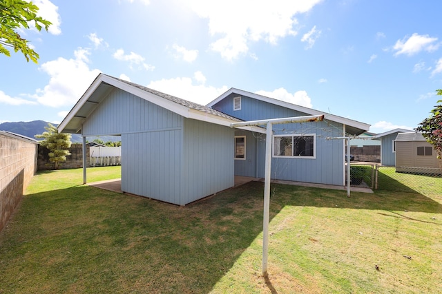 back of property featuring a lawn and an outbuilding