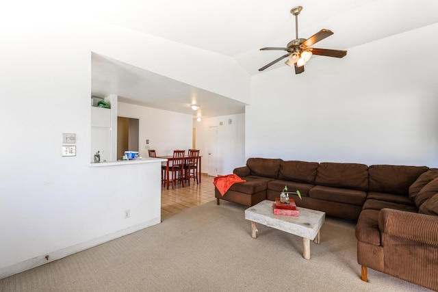 living room with ceiling fan, vaulted ceiling, and light carpet