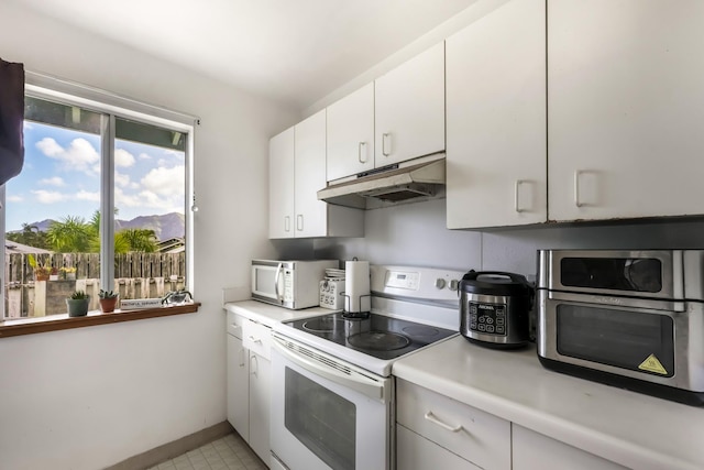 kitchen featuring a mountain view, white appliances, and white cabinets