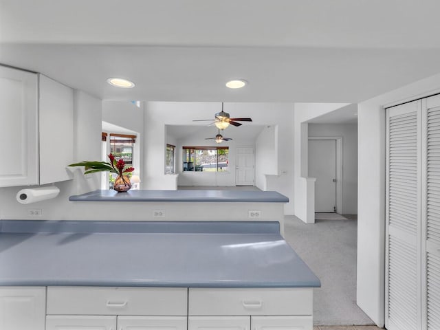 kitchen with ceiling fan, kitchen peninsula, and white cabinetry