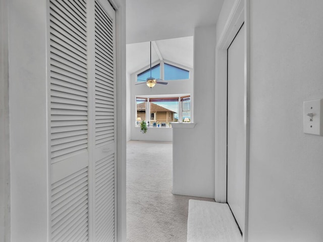 hallway with lofted ceiling and light carpet