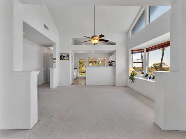 unfurnished living room featuring ceiling fan, light colored carpet, and high vaulted ceiling