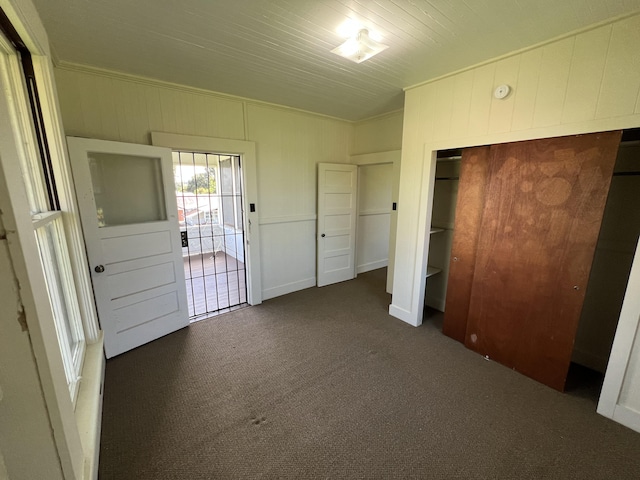 unfurnished bedroom featuring access to outside, a closet, and dark colored carpet