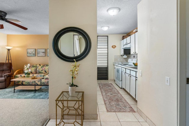 kitchen with light tile patterned flooring, white cabinets, a textured ceiling, and white range with electric cooktop