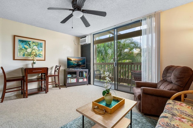 carpeted living room with ceiling fan, a wall unit AC, expansive windows, and a textured ceiling