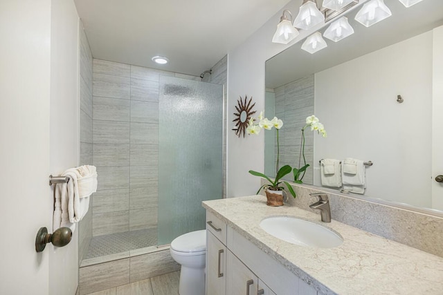 bathroom with vanity, toilet, and a tile shower