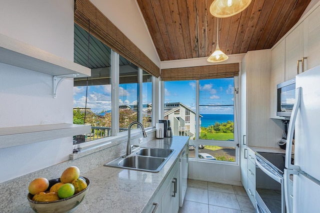 kitchen with sink, appliances with stainless steel finishes, white cabinetry, a water view, and vaulted ceiling