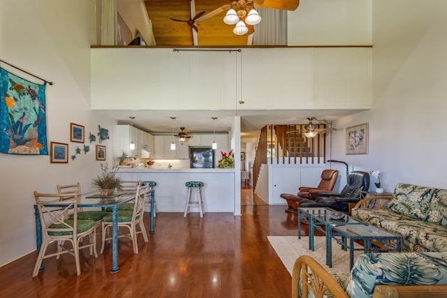 dining area featuring a towering ceiling, dark wood-type flooring, and ceiling fan