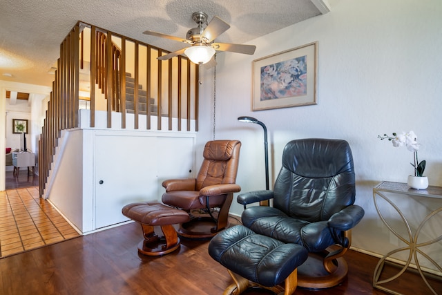 sitting room with ceiling fan, hardwood / wood-style flooring, and a textured ceiling