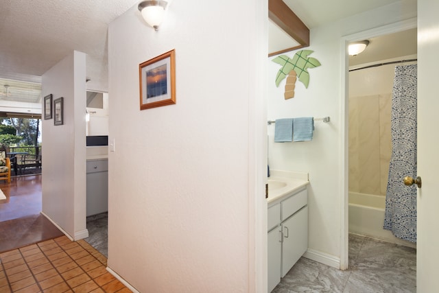 bathroom with vanity, shower / bathtub combination with curtain, and a textured ceiling