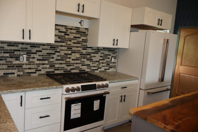 kitchen featuring gas stove, light stone countertops, high end white fridge, decorative backsplash, and white cabinets