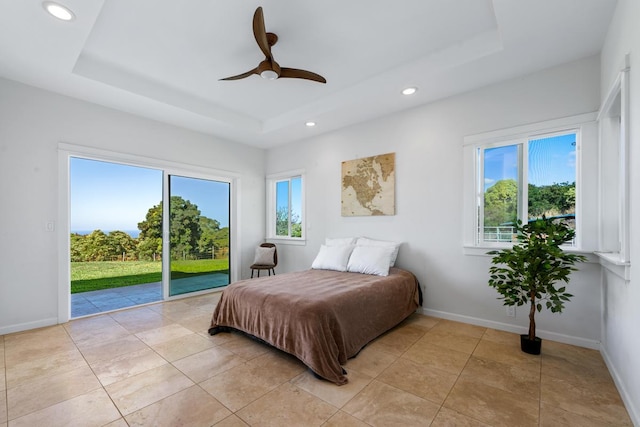 tiled bedroom featuring a raised ceiling, ceiling fan, access to exterior, and multiple windows