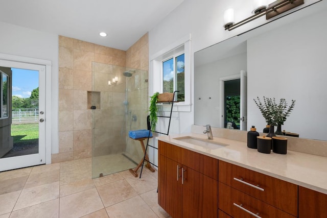 bathroom with tile patterned flooring, tiled shower, and vanity