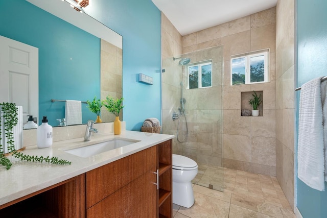 bathroom with toilet, a tile shower, and vanity