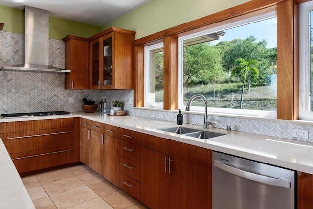 kitchen featuring wall chimney range hood, stainless steel appliances, decorative backsplash, sink, and light tile patterned floors