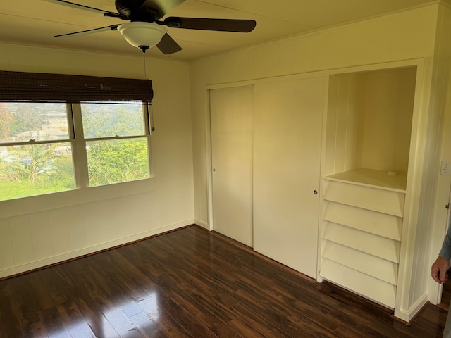 unfurnished bedroom featuring dark wood-type flooring, ceiling fan, and a closet