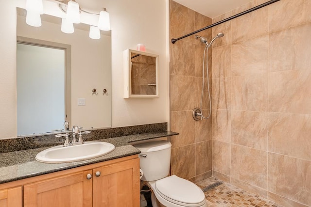 bathroom featuring a tile shower, vanity, and toilet