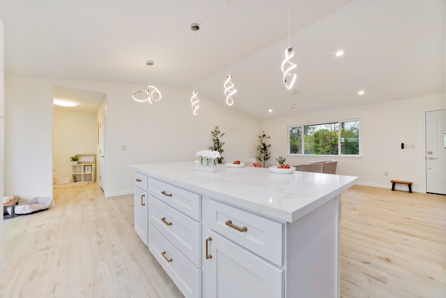 kitchen with light stone counters, decorative light fixtures, light hardwood / wood-style flooring, white cabinetry, and lofted ceiling