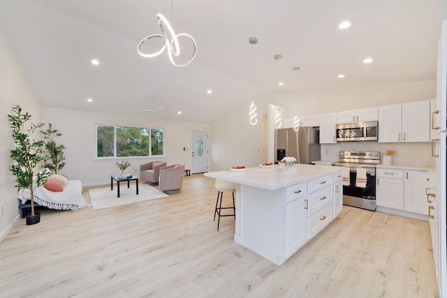 kitchen featuring a center island, white cabinetry, hanging light fixtures, and appliances with stainless steel finishes