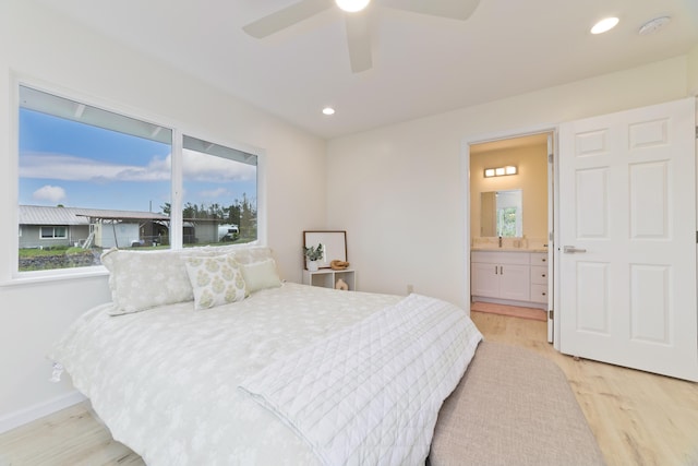 bedroom featuring multiple windows, light wood-type flooring, ensuite bath, and ceiling fan